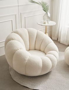 a white chair and ottoman on a rug in a living room with a potted plant