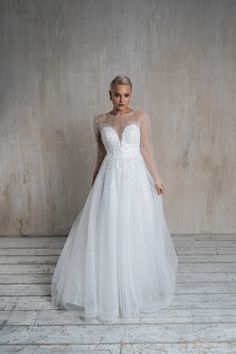 a woman in a white wedding dress standing against a wall