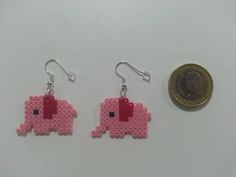 two small pink elephant earrings next to a penny