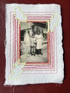 two women standing next to each other in front of a red leather surface with stitching on it