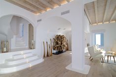 a living room filled with white furniture and wooden floors next to an archway in the wall