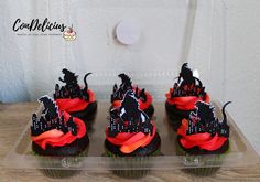 cupcakes decorated with black and red icing are on a clear platter