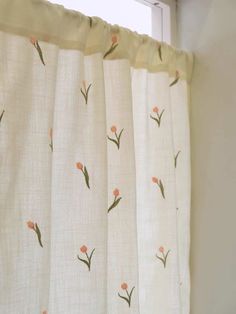 a curtain with pink flowers on it is hanging in front of a window sill