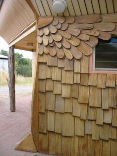 a wooden building with a fan on it's roof next to a brick walkway