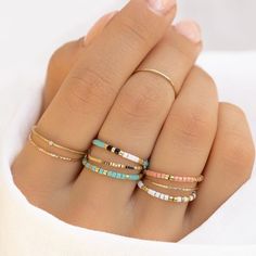 a woman's hand with five different rings on it