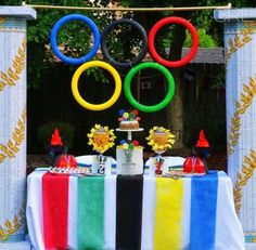 an olympic themed dessert table with cake and decorations in the shape of rings on it