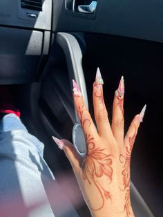 a woman's hand with pink and white nail polish on her nails in a car