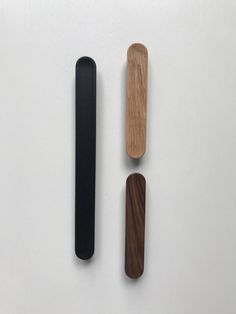 three different types of wooden objects on a white surface, one black and one brown