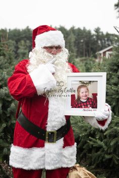 a man dressed as santa claus holding up a picture frame with a child in it