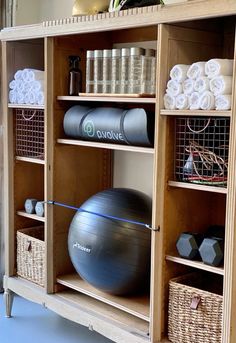 an exercise ball sits on top of a wooden shelf next to some baskets and towels