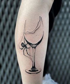 a black and white photo of a wine glass tattoo on the right leg, with a skull in it