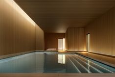 an indoor swimming pool with wooden slats on the walls and floor, next to a large window