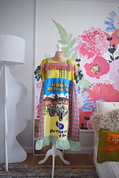 a dress on a mannequin in front of a colorful wallpapered room