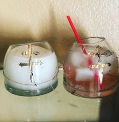 two candles with crosses painted on them are sitting next to each other in glass bowls