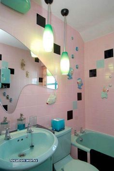 a bathroom with pink walls and black and white tiles on the wall, blue tub, toilet and sink