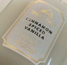 a bottle of cinnamon spiced vanilla sitting on top of a white tablecloth with gold trim