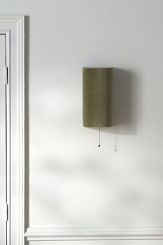 a lamp that is on the side of a white wall next to a door and window