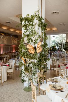 the tables are set up with white linens and gold chargers, which have butterflies on them