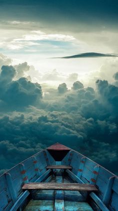 an empty boat in the middle of some water with clouds above it and a bench at the end