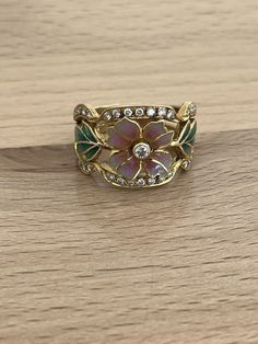 This exquisite Masriera Art Nouveau ring showcases asymmetrical brilliant cut diamonds set in 18kt yellow gold with plique à jour enamel accents. The vintage piece features a multicolor design and is signed by the artist. The ring is size 8.5 and has a pave setting style, making it perfect for any occasion. The Loupe Clean gemstone clarity grade and Excellent cut grade give the diamonds a stunning sparkle. This handmade, natural creation is a one-of-a-kind addition to any fine jewelry collection. Look at our pictures you will receive what you see. Also note that these are all hand finished that been said even if these where mass produced which they are not they would all look different the craftsmanship is unique in each one this is one of our many unique pieces of jewelry we have to sell Enamel Rings Vintage, Art Nouveau Wedding Ring, Art Deco Jewelry Rings, Cottagecore Wedding, Enamel Rings, Art Nouveau Weddings, Art Nouveau Ring, Nouveau Jewelry, Art Nouveau Jewelry