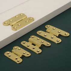 four different types of brass door handles on a green surface with two white boxes in the background