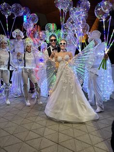 a bride and groom pose for a photo in front of an array of people dressed up as tinkerbells