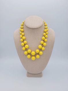 "Vintage 2 Strand Plastic Yellow Beaded Choker Bib Necklace  This colorful necklace makes a great statement piece.  Two strands of yellow plastic beads make up this piece.  The beads gradually increase in size to the midpoint.  The piece secures with a lobster claw clasp & is adjustable for length.  This piece is in excellent vintage condition with very little wear.   Dimensions: 20 1/2\" maximum Clasp: Lobster Claw Markings: None Condition:  Excellent - very little wear All of my shop items are Plastic Beaded Necklace With Round Beads, Yellow Plastic Party Jewelry, Yellow Beaded Chain Necklace For Party, Party Jewelry With Large Yellow Beads, Yellow Necklaces With Faceted Beads, Yellow Necklace With Faceted Beads, Yellow Double Strand Beaded Necklace, Colorful Necklace, Retro Women