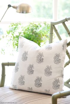 a white pillow sitting on top of a chair next to a window