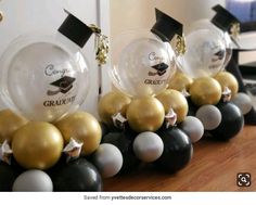 graduation decorations are lined up on a table with black, white and gold balloons in the middle