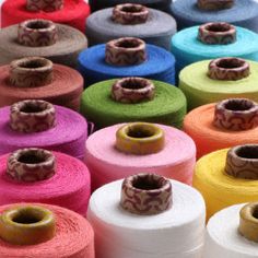 many spools of colorful thread sitting on top of each other