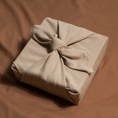 a wrapped present box with a bow on it's side sitting on a bed