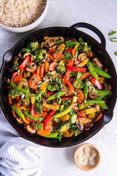 a skillet filled with stir fry vegetables and rice