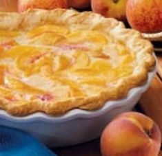 a pie sitting on top of a wooden table next to peaches