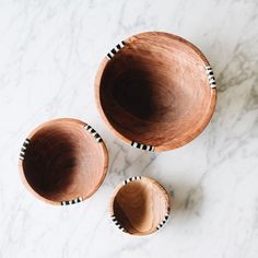 three wooden bowls sitting on top of a marble counter