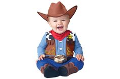 a baby sitting on the ground wearing a cowboy hat