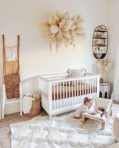 a baby in a white crib next to a wall with feathers hanging from it