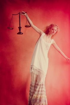 a woman standing in front of a scale with her arms outstretched and holding the scales above her head