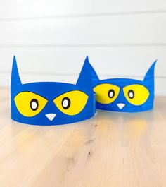 two blue and yellow cat crowns sitting on top of a wooden table