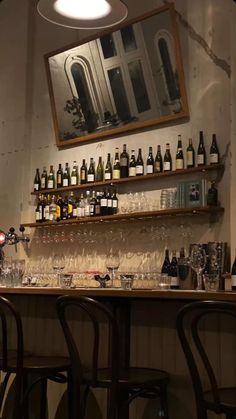 the bar is filled with many bottles and glasses on it's shelves, along with several empty wine glasses