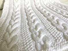 a white knitted blanket sitting on top of a bed