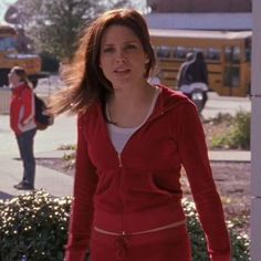 a woman in a red dress is walking down the street with her hand on her hip