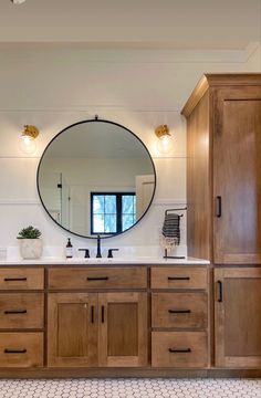 a bathroom with wooden cabinets and a round mirror