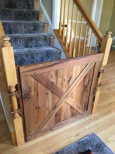 a wooden gate on the stairs leading up to a set of blue carpeted stairs