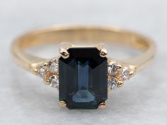 an emerald and diamond ring is shown on a white surface with two diamonds around it