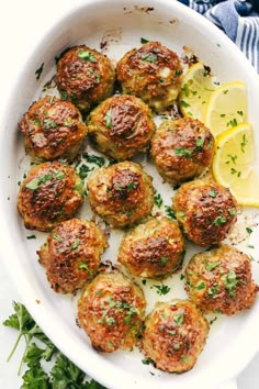 a white plate topped with meatballs and lemon wedges