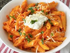 a white bowl filled with pasta and cheese on top of a red and white table cloth