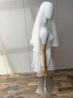 a white mannequin with a veil on it's head is standing in front of a wall