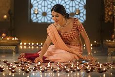 a woman sitting on the ground surrounded by candles