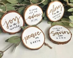 four wood slices with names on them and some green leaves around the edges that read, i come to jesus adore him