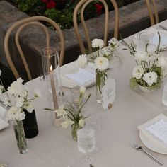 the table is set with white flowers and place settings